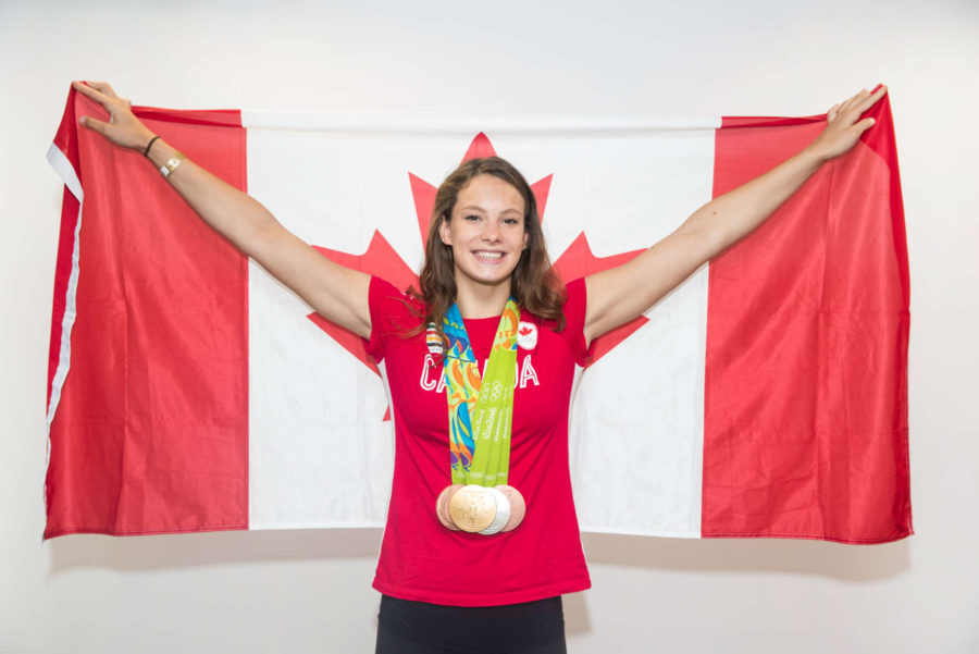 Canada's Penny Oleksiak poses with her medals on the flag at the Olympic games in Rio de Janeiro, Brazil, Sunday August 21, 2016. COC Photo/Mark Blinch